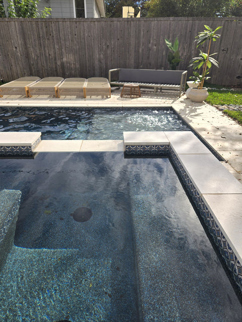 Backyard with a pool, lounge chairs, and a wooden fence.

